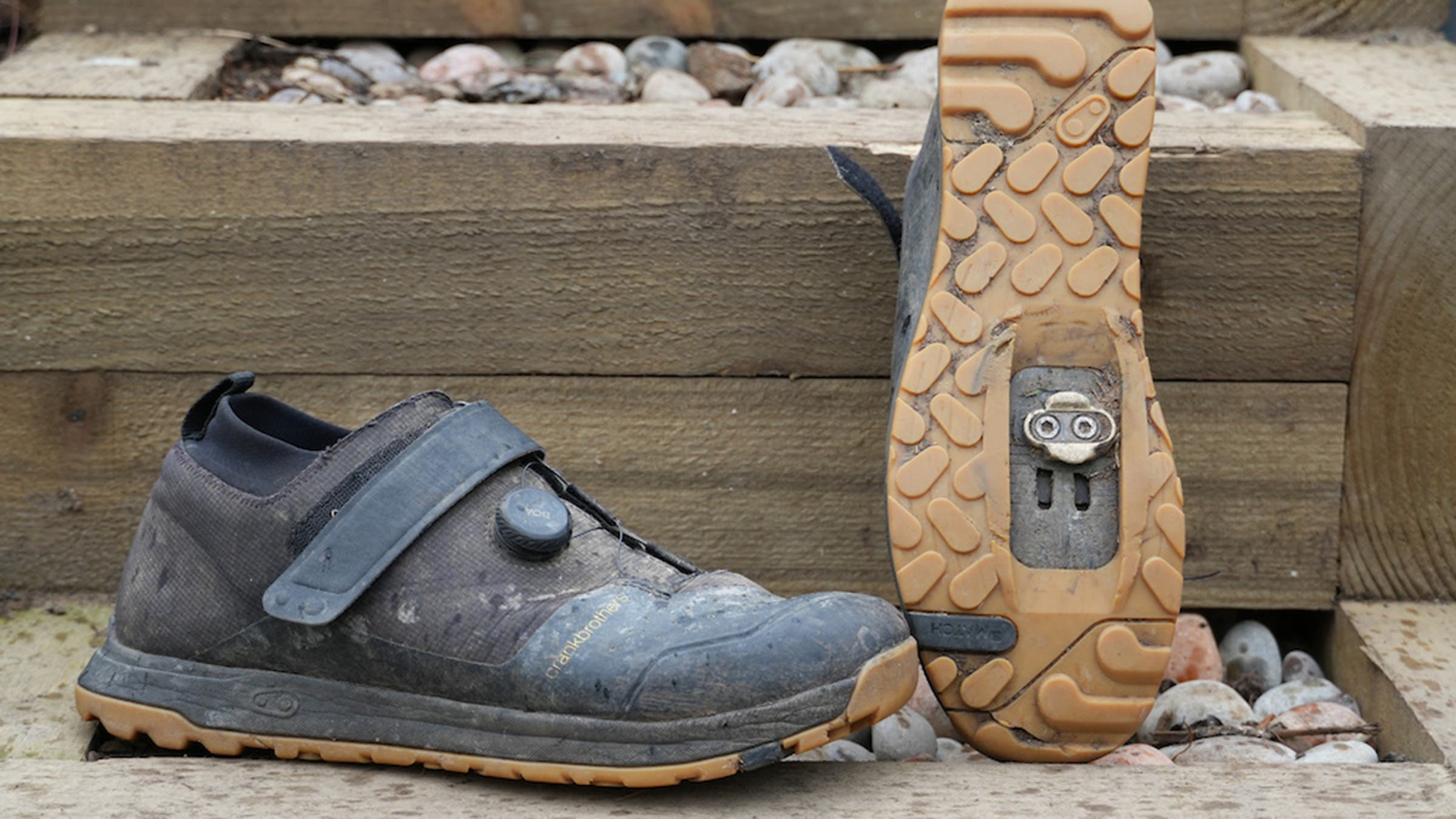 Dirty black mountain bike shoes displayed on wooden step