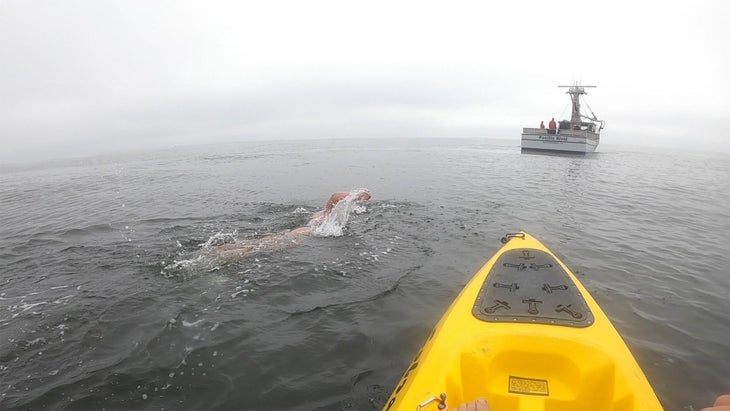 A kayak paddles next to swimmer Amy Appelhans Gubser. 