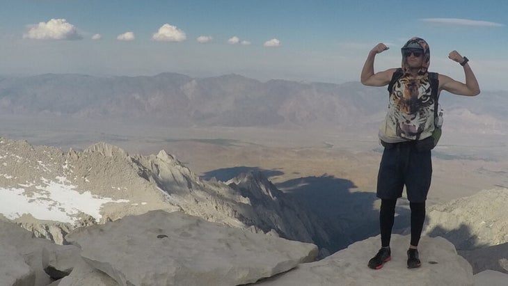 The author, wearing a shirt with the image of a tiger and flexing his arms, atop Mount Whitney, California, the tallest peak in the contiguous U.S.