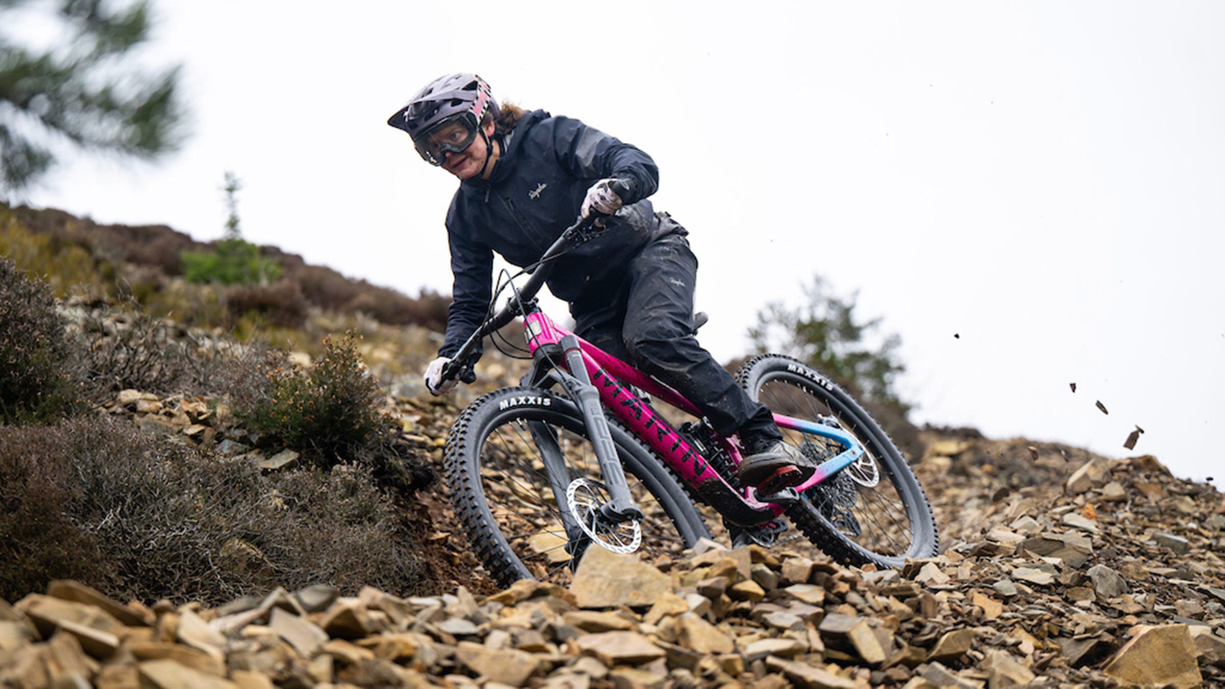 Woman riding pink enduro bike on rocky trail