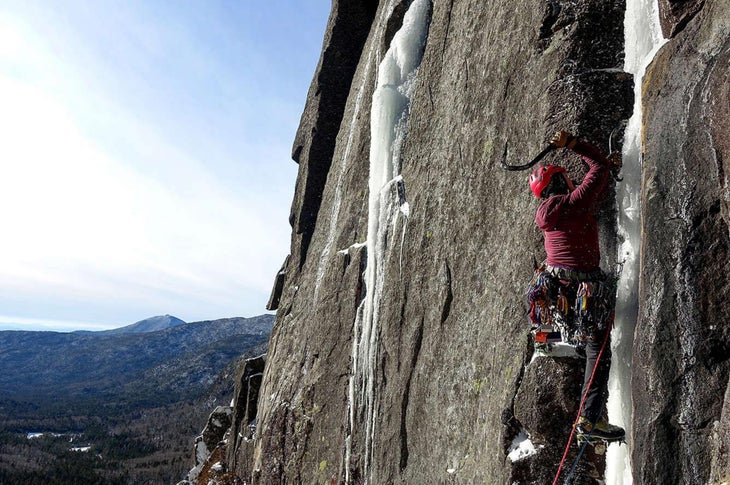 Robbi Mecus ice climbs on a small piece of ice amongst a broad rocky cliffband