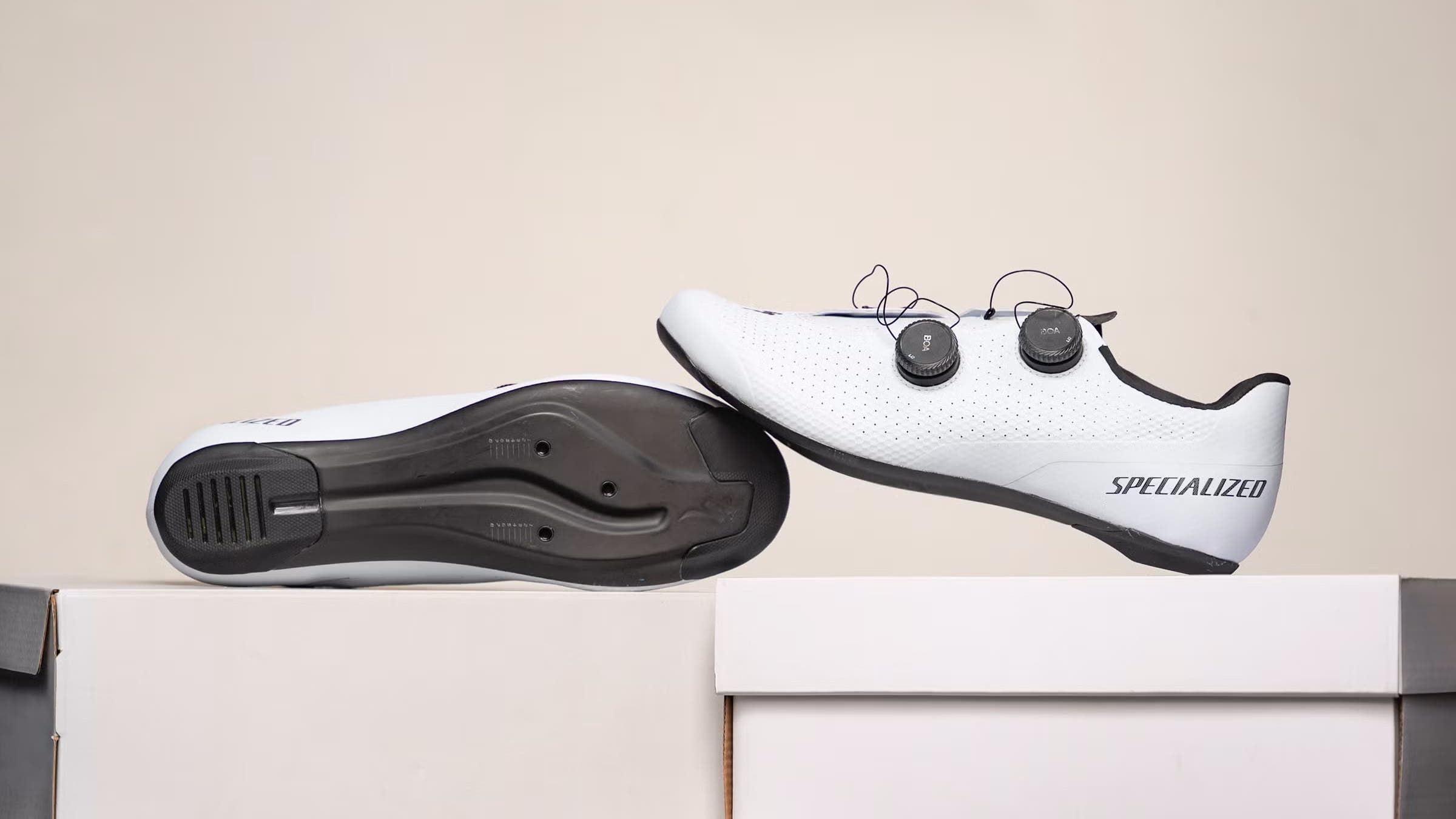 White Specialized cycling shoes displayed on off-white shoeboxes on off-white background