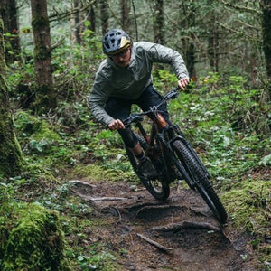 Male mountain biker on Trek Slash+ electric mountain bike on wooded singletrack trail