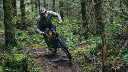 Male mountain biker on Trek Slash+ electric mountain bike on wooded singletrack trail