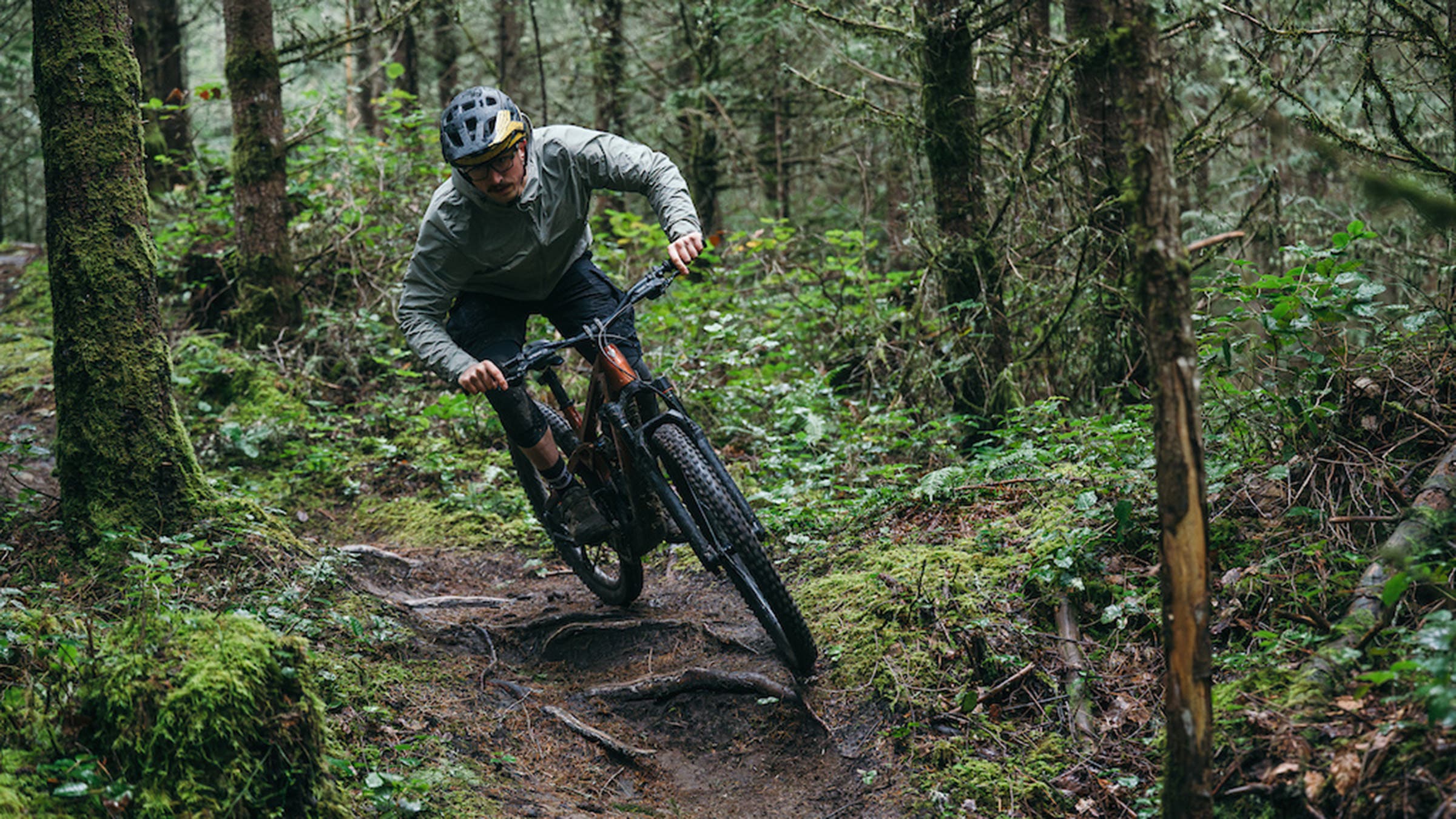 Male mountain biker on Trek Slash+ electric mountain bike on wooded singletrack trail