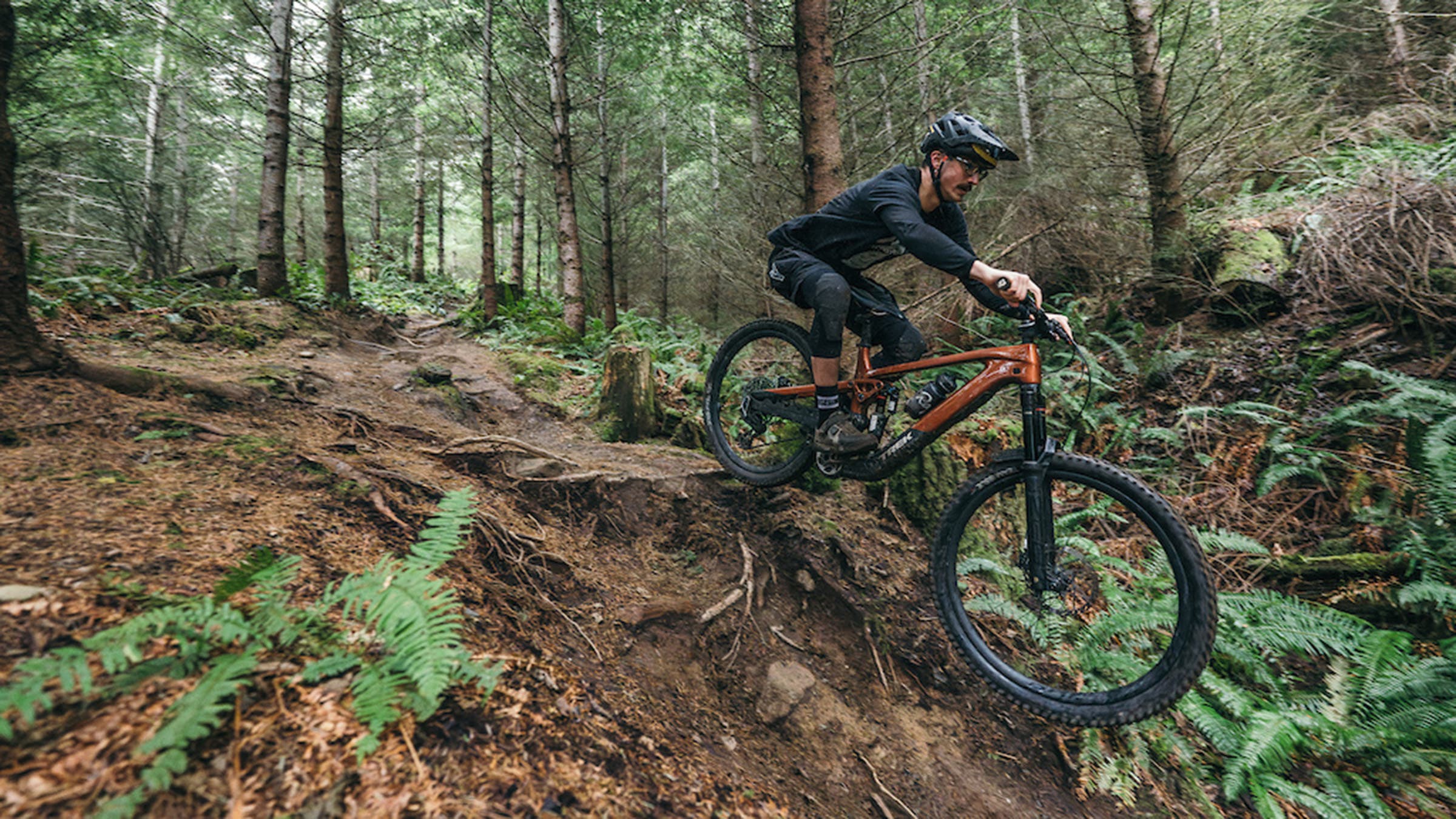 Male mountain bike rider on Trek Slash+ electric mountain bike on wooded downhill trail 