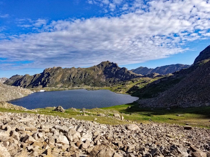 Mountain ridge popping up from behind a lake and meadow