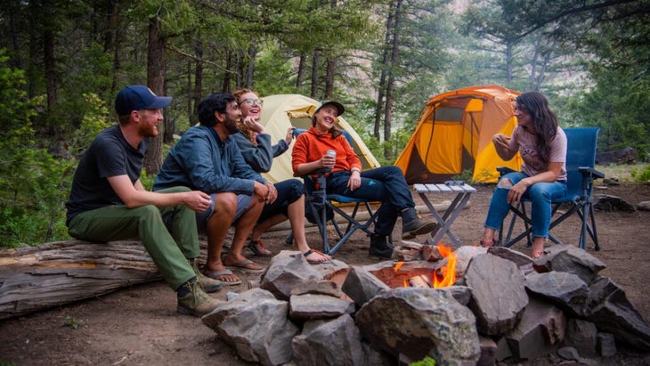A group of campers are seated around a fire at Campfire Ranch in Colorado.