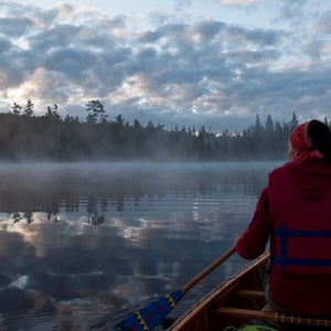 woman canoeing on a foggy morning with orange life vest