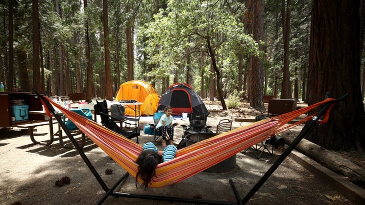 Two girls, one lazing on a hammock, hang out at their campsite in Yosemite National Park.