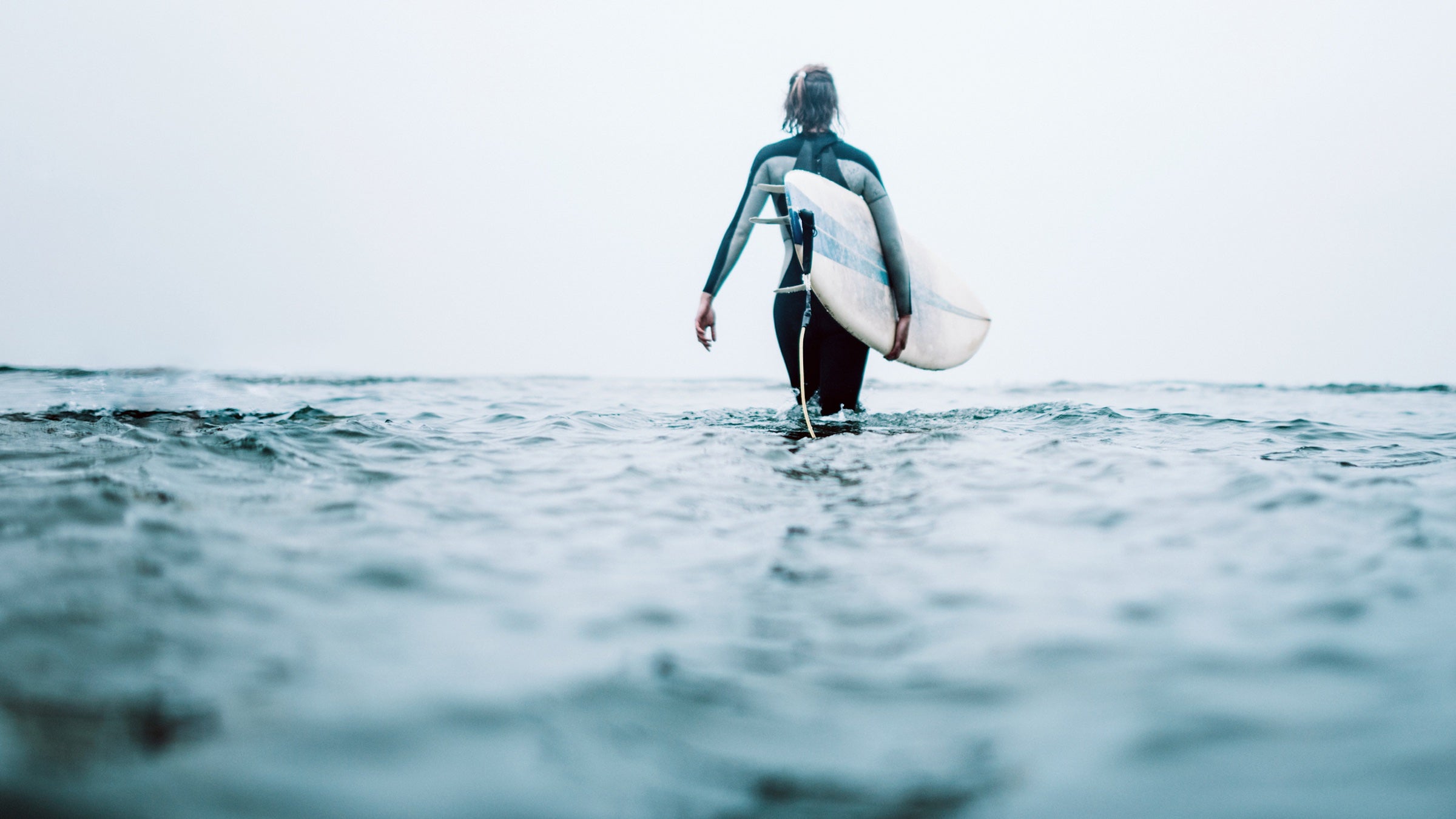 a woman walking out to surf on a cloudy day