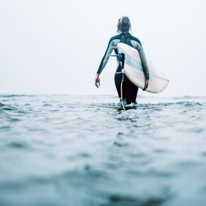 a woman walking out to surf on a cloudy day