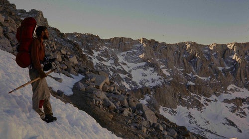 Hiker on high snowy mountain with ice axe