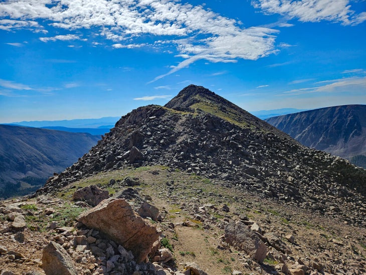 mountain trail leading to summit on a blue sky and cloudy day