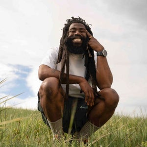 Malik Martin, known as Malik Tha Martian, kneels in a field