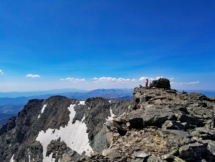 Large summit cairn on mountain with steep glacier