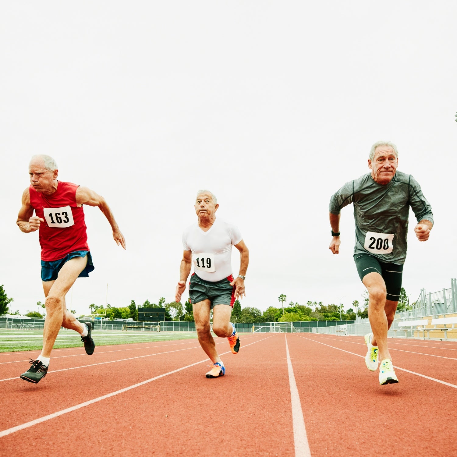 Three older men running a rac e on a rtrack