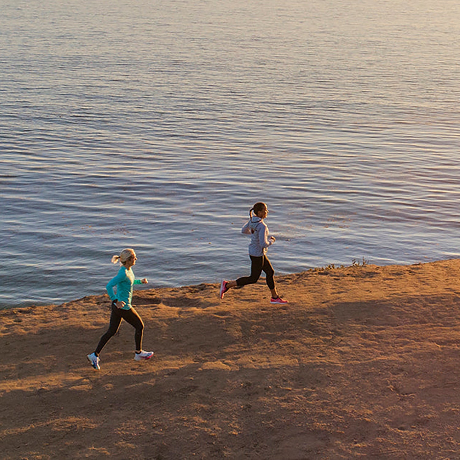 two women running along coastal bluffs