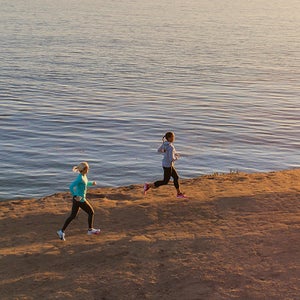 two women running along coastal bluffs