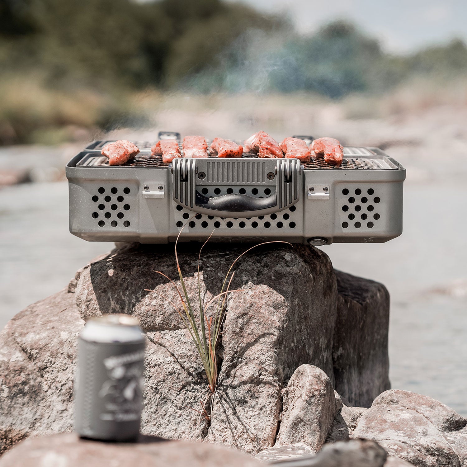 open portable grill on rock in front of lake