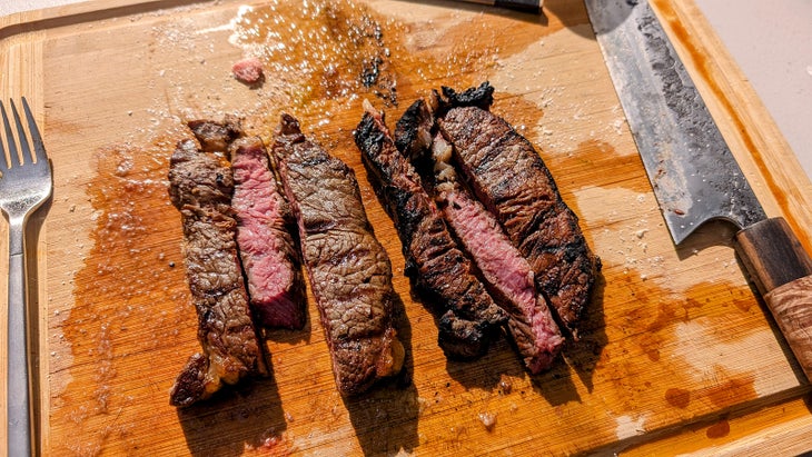 grills steak cut up on a cutting board