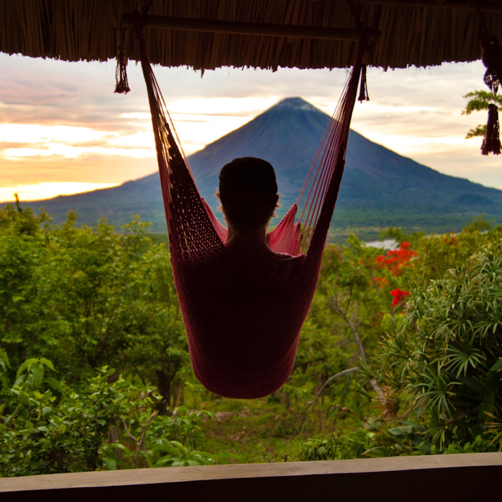 A man sits in a hammock looking out at Concepción volcano in Nicaragua.