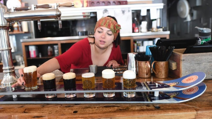 A girl serves a flight of beers at a brewery in Aspen, Colorado. Landing a job before you move to a mountain town is generally a smart course of action. 