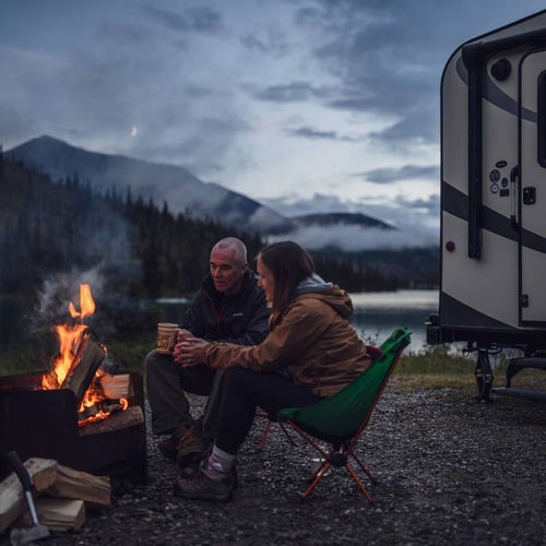 A couple enjoys a bonfire at Summit Lake campground as the moon rises over the Northern Rockies.