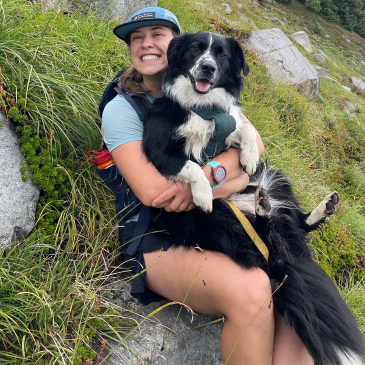 Female hiker with black and white dog on lap during a hiking rest