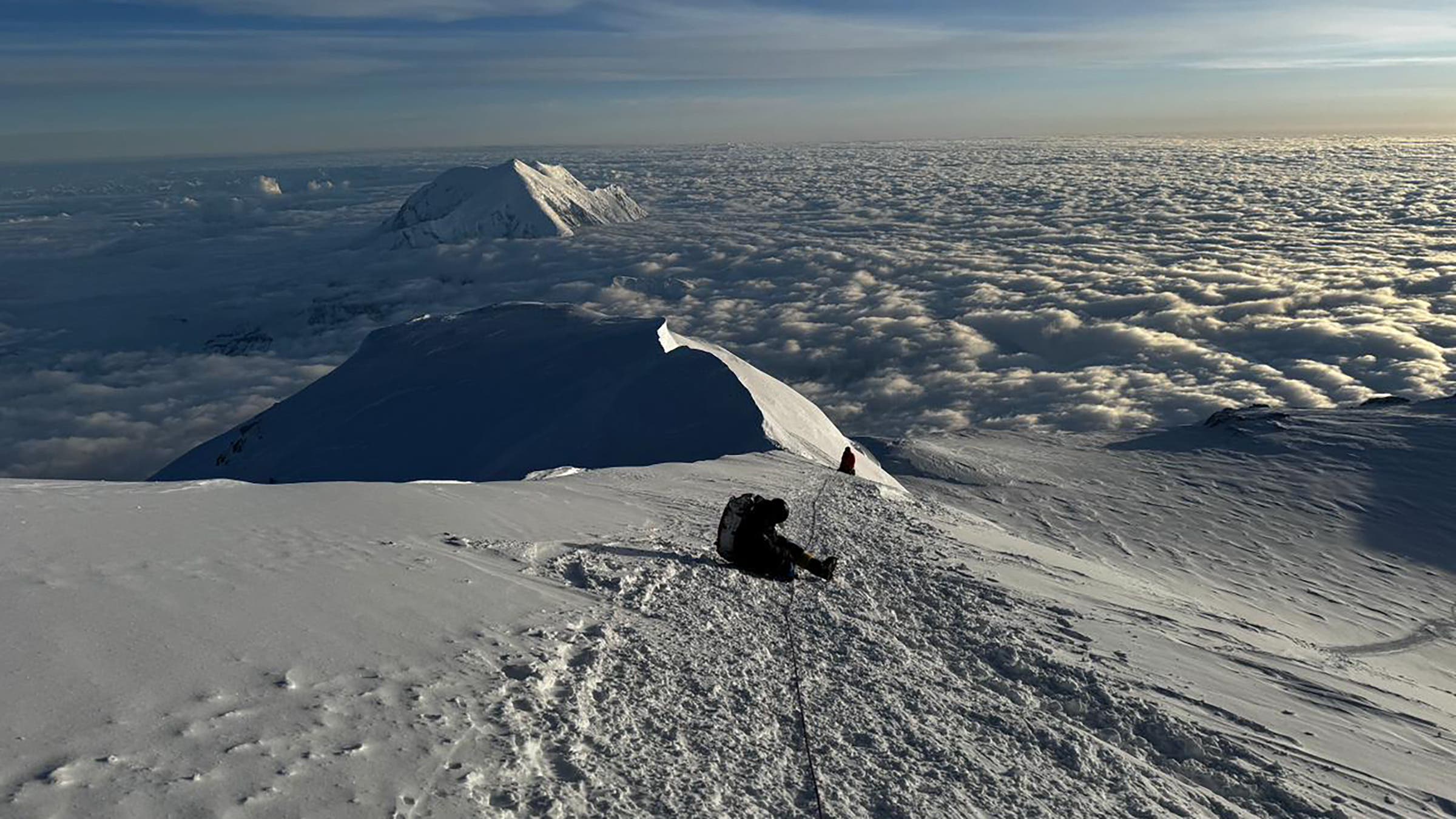 A climber sits in the pathway on Denali