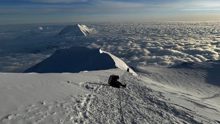 A climber sits in the pathway on Denali