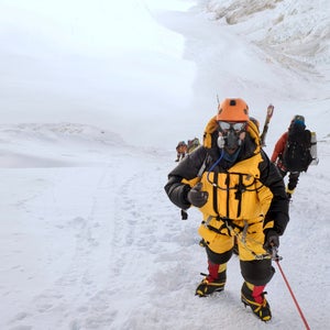 A climber in an oxygen mask giving a thumbs up on Mount Everest