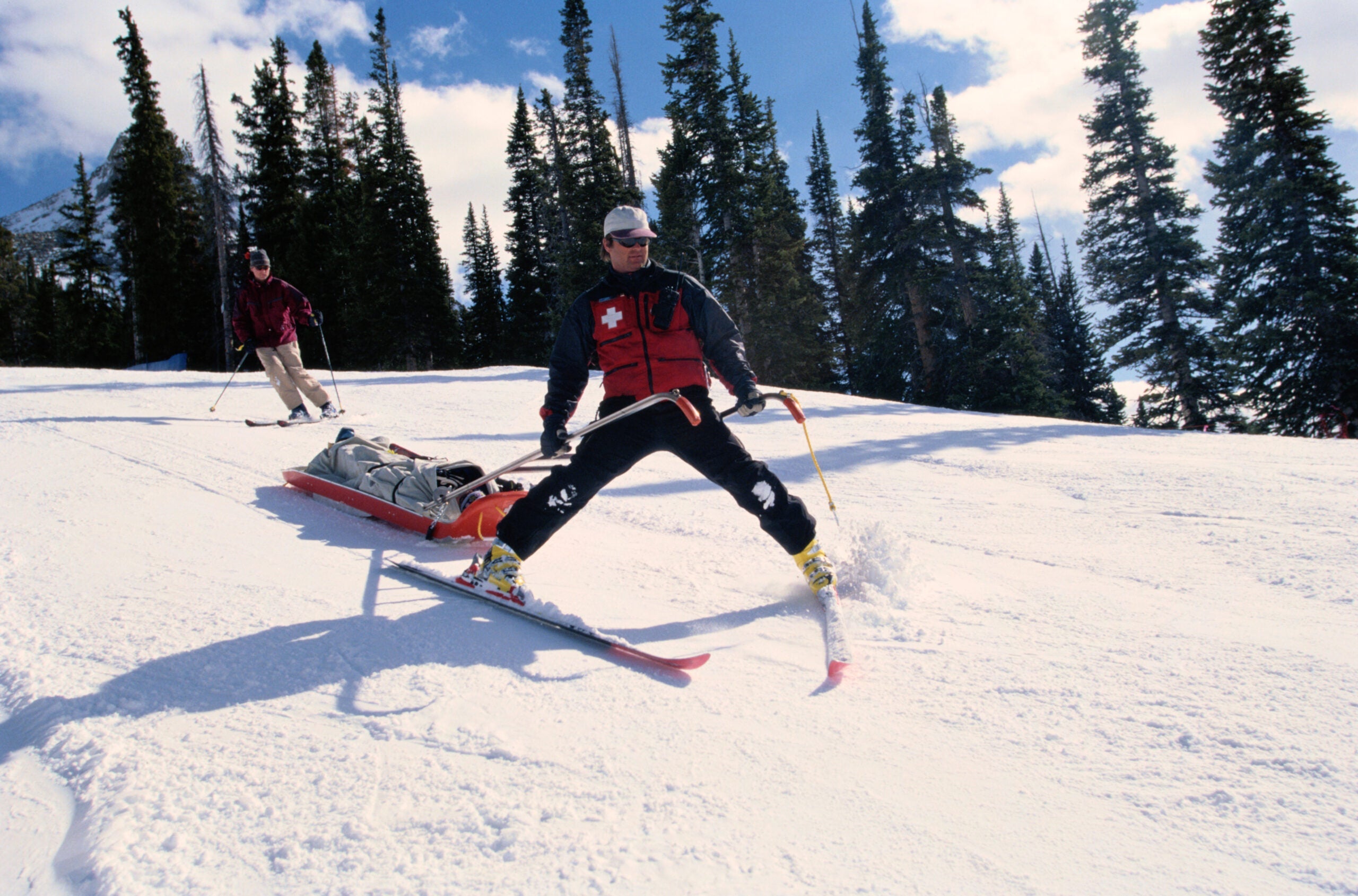 ski patrol skiing down with toboggan