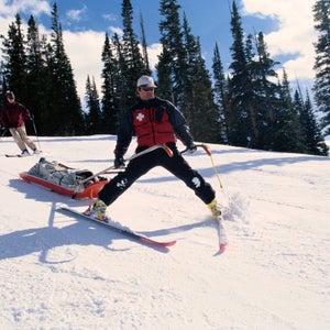 ski patrol skiing down with toboggan