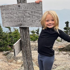 A small child stands on top of a mountain in New England
