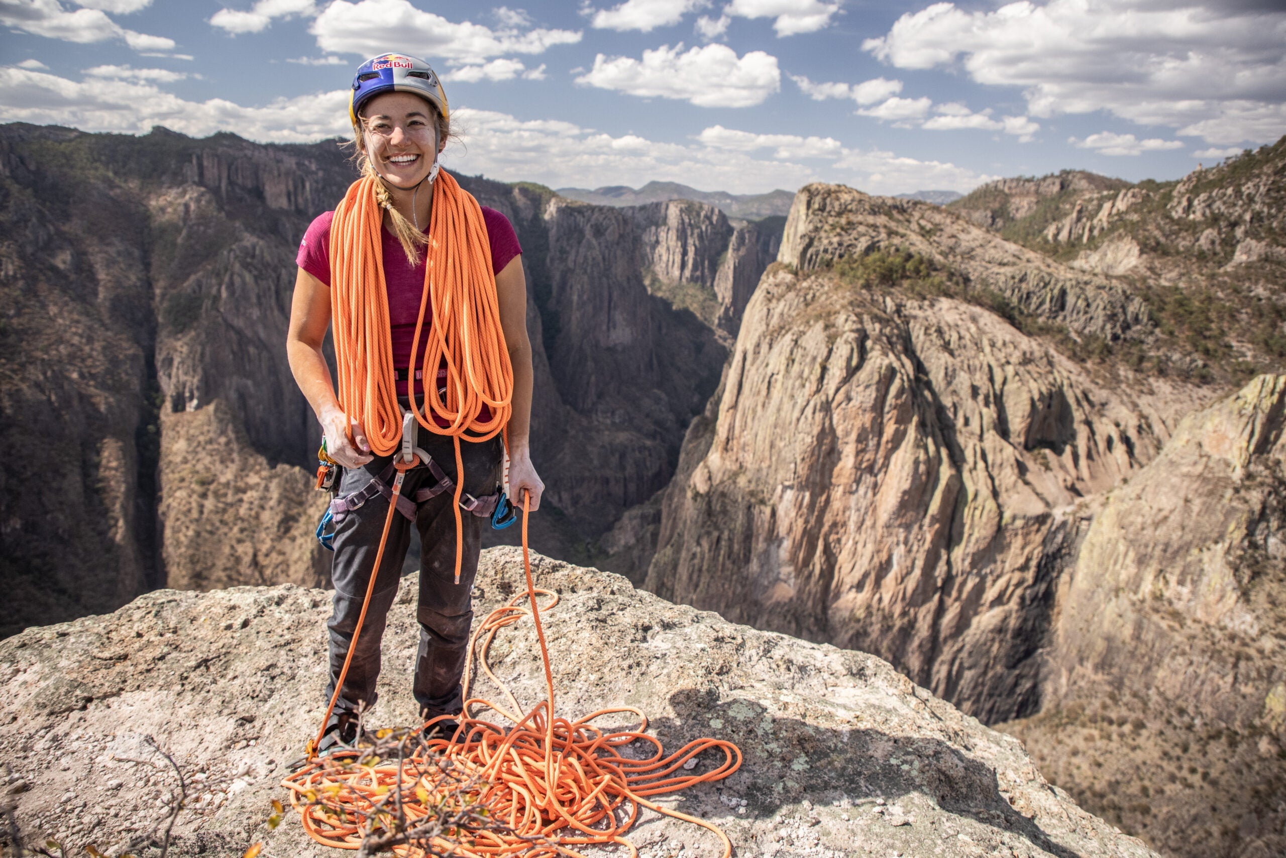 Sasha DiGiulian coiling a rope on top of a cliff.