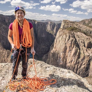 Sasha DiGiulian coiling a rope on top of a cliff.