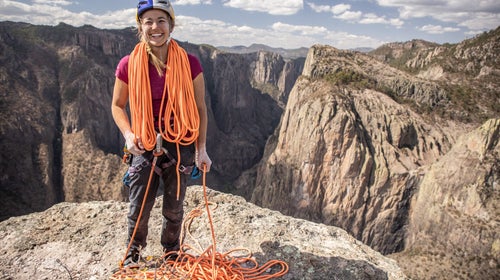 Sasha DiGiulian coiling a rope on top of a cliff.
