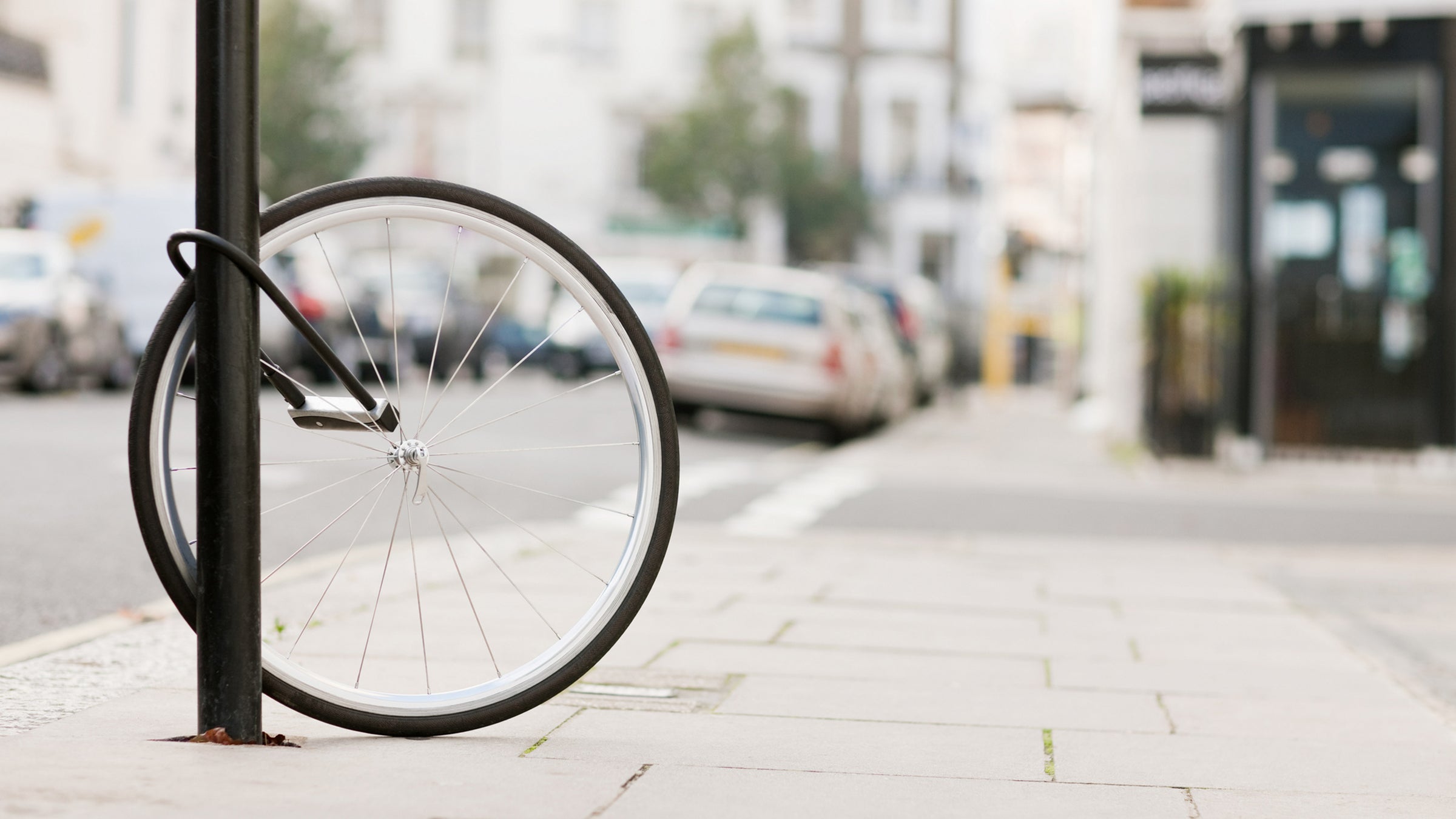 Bike wheel with lock attached to lamp post on street after bike stolen