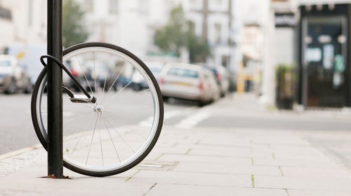 Bike wheel with lock attached to lamp post on street after bike stolen