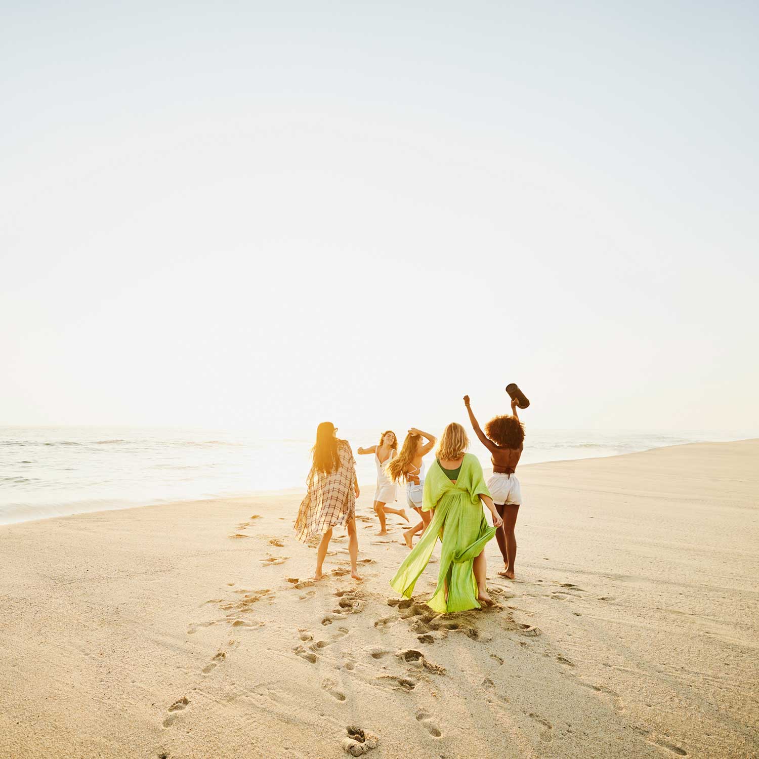 women on a beach with a portable speaker