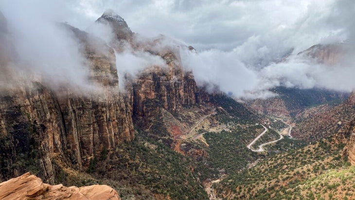 Low clouds hover over the rock massifs and valley at Zion National Park, as seen from the end of the Canyon Overlook Trail.