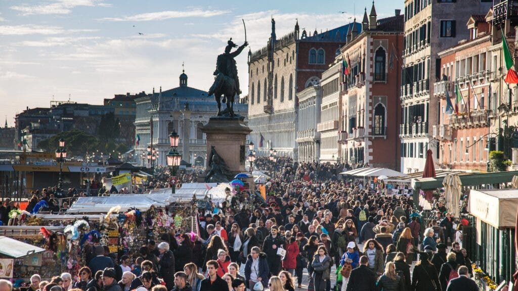 Crowds of tourists pack the streets of Venice, Italy.