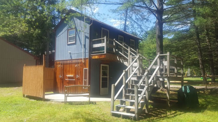 a two-story cabin with steps and a grill at Dyer Woods Nudist Campground