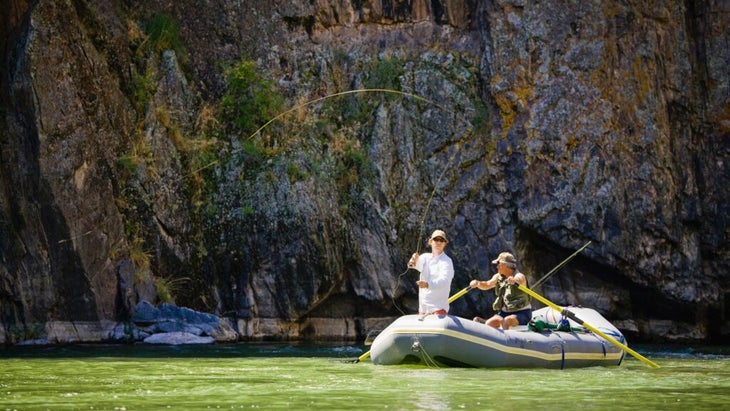 Two men raft down Colorado’s Gunnison River, one casting his fly rod, the other plying the water with two oars.