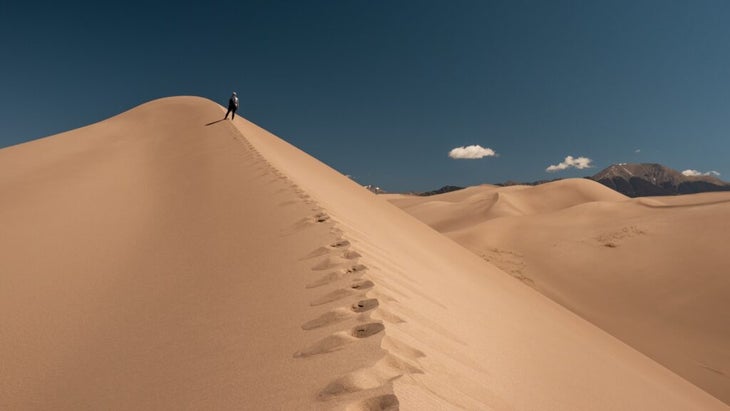 The writer nears the top of a massive sand dune at Great Sand Dunes National Park and Preserve in Colorado