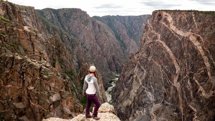 The author standing at the Painted Wall Overlook of Black Canyon of the Gunnison National Park, looking down at the Gunnison River.
