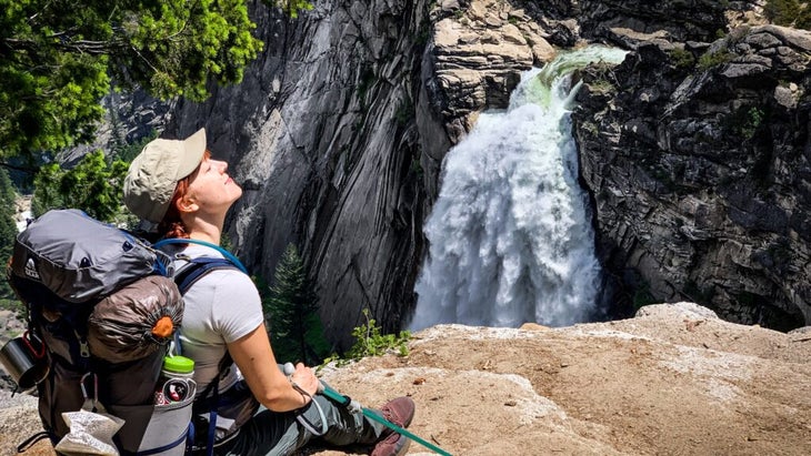 The author sits on a rocky overlook and turns her head up to the sun. Yosemite鈥漵 Illilouette Falls is right below her.