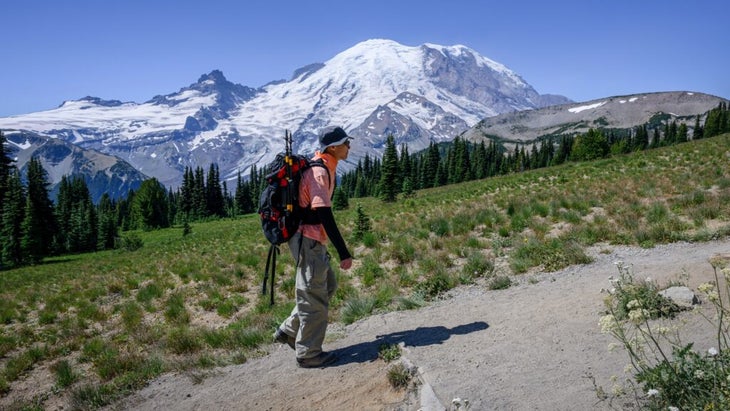 A man hikes Sunrise Trail at Washington’s Mount Rainier National Park in summer.