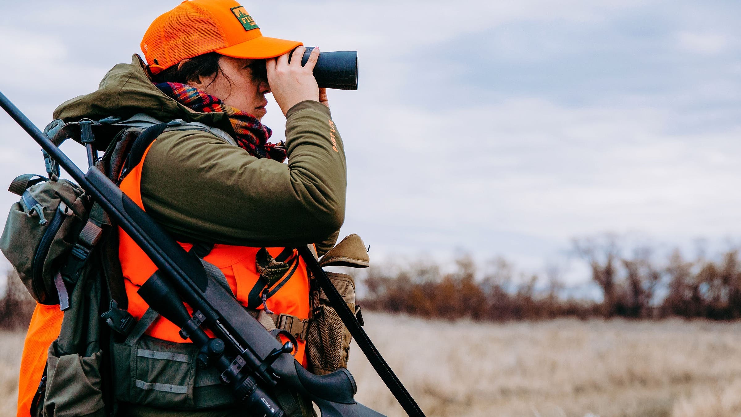 Woman looking through binoculars while deer hunting in Montana. Beef-loving environmentalist